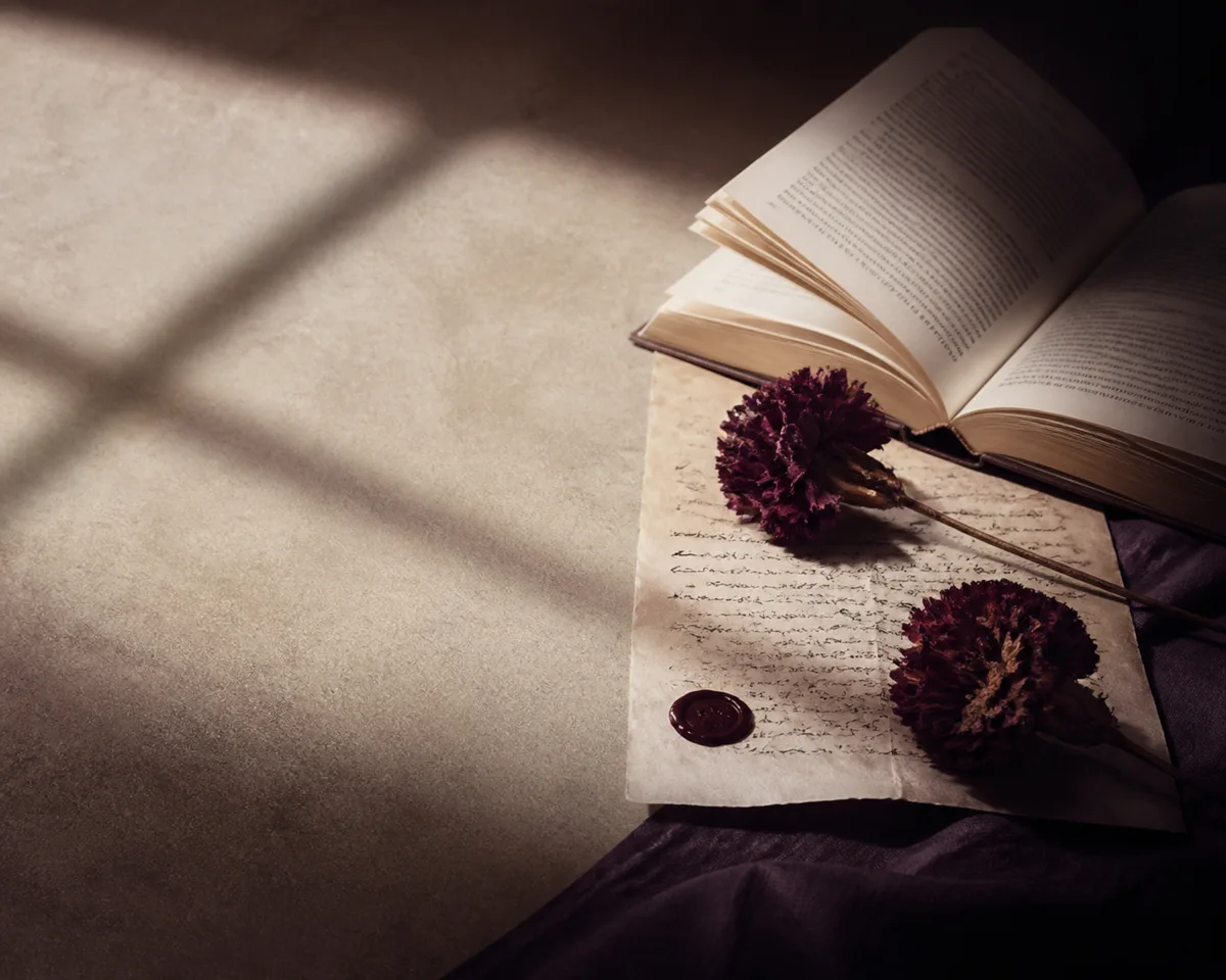 Buku terbuka, surat, bunga burgundy, dan segel lilin dalam suasana membaca yang intim.